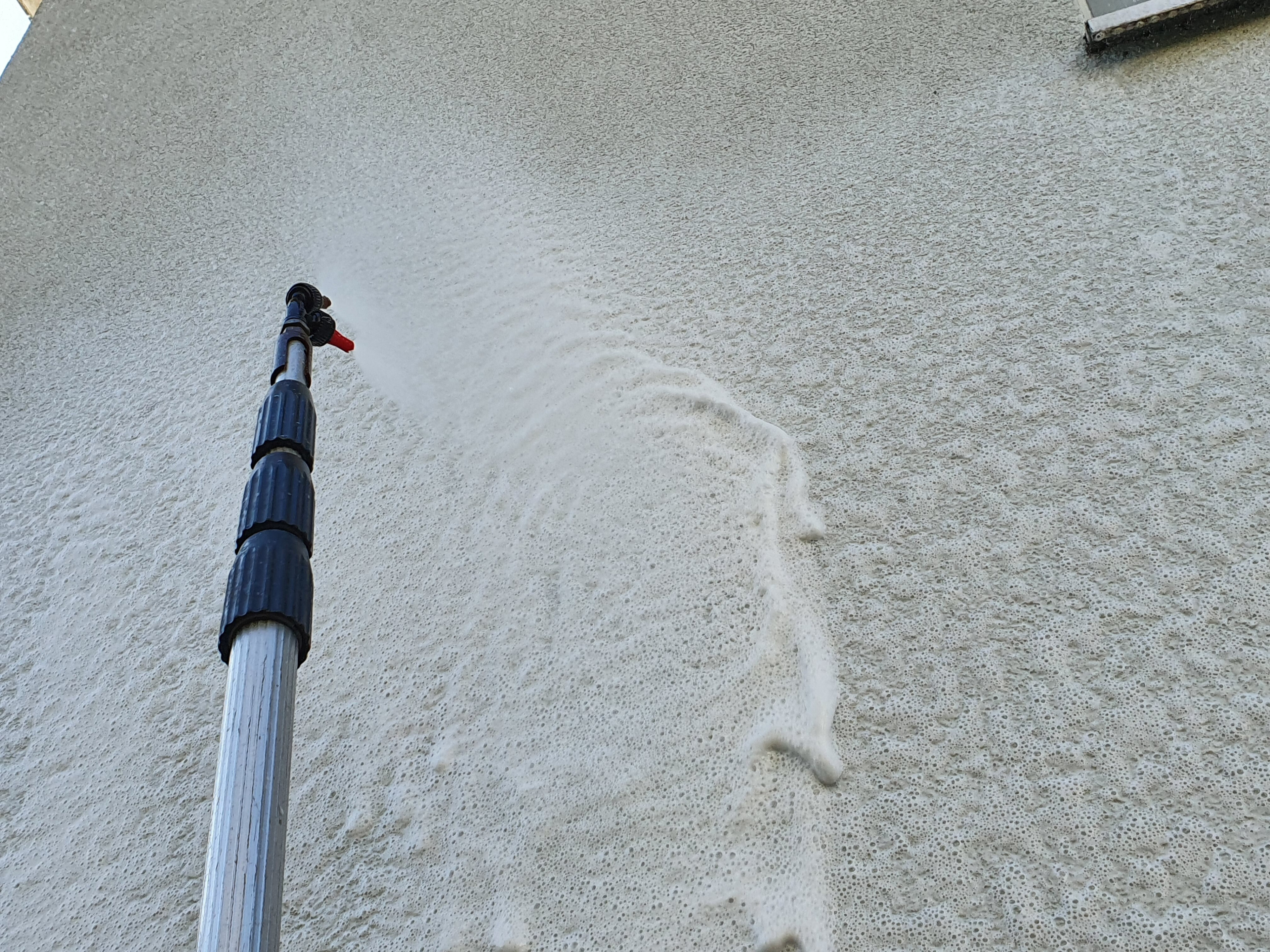 Sprühkopf beim Aufschämen vom Grünbelagentferner an der Fassade.