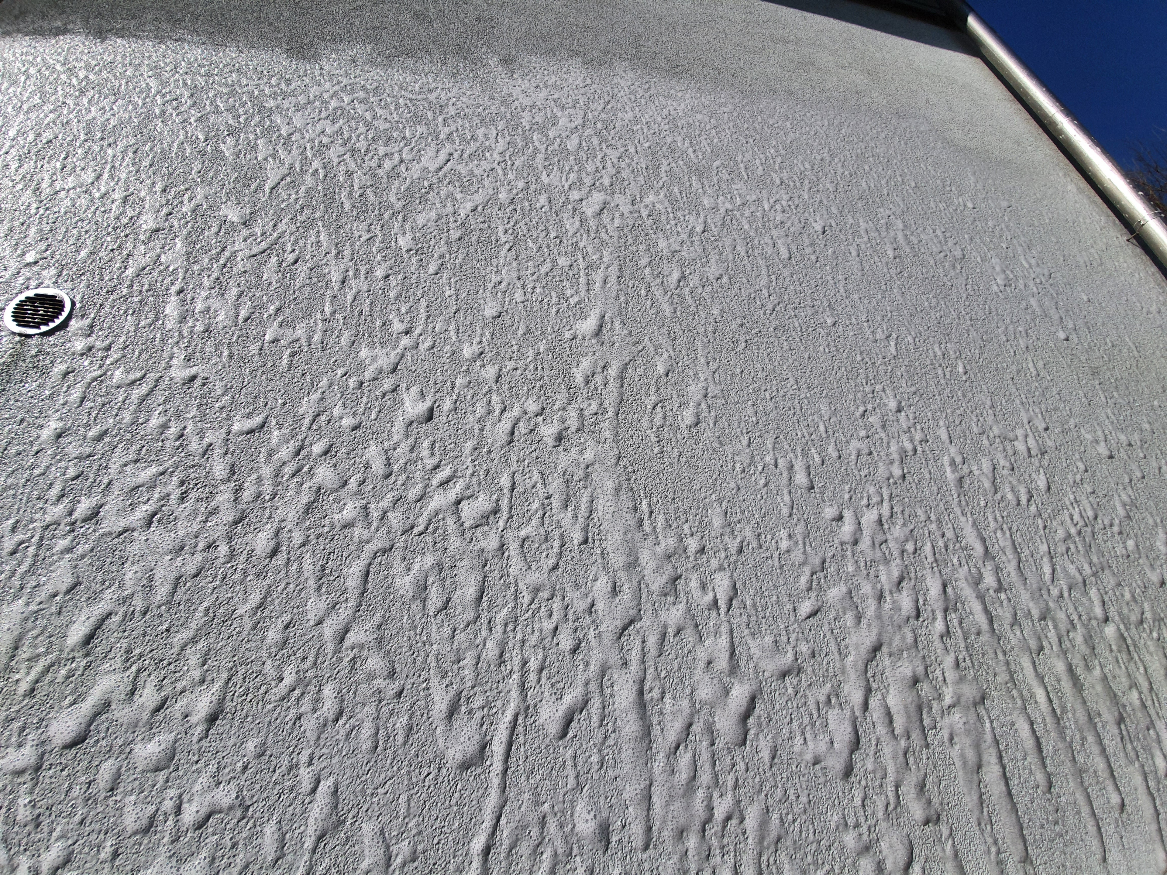 Aufgetragener Schaum mit Grünbelagentferner Ago Quart an einer Fassade.